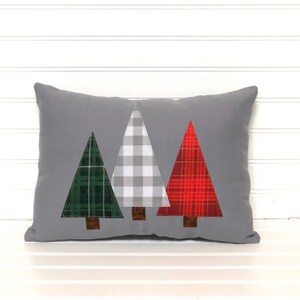 May include: A gray throw pillow with three appliqu&eacute;d Christmas trees. The trees are green, white and red plaid.