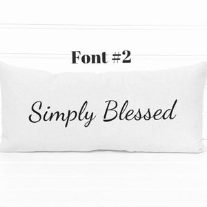 May include: White rectangular pillow with the text "Simply Blessed" in a cursive font.