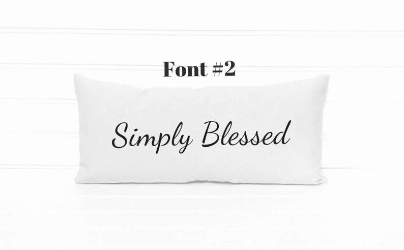 May include: White rectangular pillow with the text "Simply Blessed" in a cursive font.
