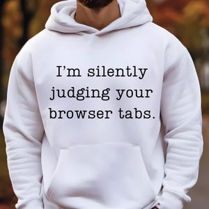Op de afbeelding: Witte hoodie met de tekst "Ik beoordeel je browsertabbladen in stilte."