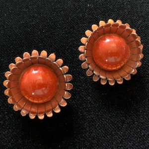 May include: A pair of copper earrings with orange enamel flower designs.