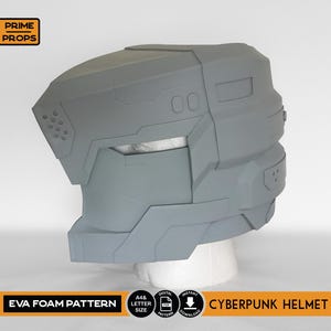 May include: A gray EVA foam Cyberpunk helmet, displayed on a white mannequin head. The helmet features a geometric design with angular panels, vents, and a visor area. The text "EVA FOAM PATTERN" and "CYBERPUNK HELMET" are visible.
