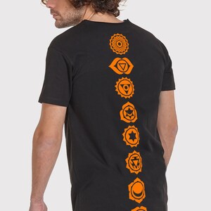 Pode incluir: Camiseta preta de manga comprida com um design laranja de sete chakras nas costas.