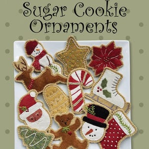 May include: A collection of felt sugar cookie ornaments in various shapes, including a snowman, star, reindeer, candy cane, mitten, Santa, Christmas tree, teddy bear, and stocking. The ornaments are approximately 3 to 5 inches in size.