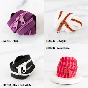 May include: Four coiled zippers: SSCZ29 Plum is purple with matching pulls, SSCZ30 Cowgirl is white with brown teeth and pulls, SSCZ31 Black and White features black tape with white teeth and pulls, and SSCZ32 Jam Stripe has red and pink stripes.