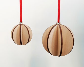 May include: Two wooden Christmas ornaments with red ribbon hangers. The ornaments are made of thin wood strips that are layered to create a sphere shape. The larger ornament is about 4 inches in diameter, and the smaller ornament is about 3 inches in diameter.