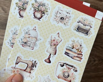 May include: Two sheets of decorative stickers with a vintage theme. The stickers feature illustrations of flowers, a camera, a typewriter, a birdcage, a dress form, a sewing machine, a teapot, and a telephone. The text "love from" is at the top.