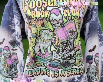 May include: A dark blue and white acid-wash sweatshirt featuring a graphic of a skeleton with a pink mohawk reading a book next to a bulldog. The text reads Goosebumps Book Club and Reading is a Scream. Marley Rose Customs is printed on the front.