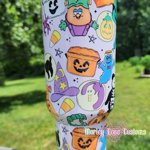 May include: A white stainless steel tumbler featuring a repeating pattern of colorful Halloween-themed cartoon characters, including a pumpkin bucket, a ghost, a witch hat, candy corn, and a Frankenstein-like figure, with the text Marley Rose Customs.