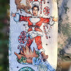 May include: A white and green sweatshirt featuring a cartoon illustration of a person dressed as Santa Claus, surrounded by Christmas-themed elements like candy canes, a squirrel, and a roasted turkey. The design has a distressed, bleached effect.
