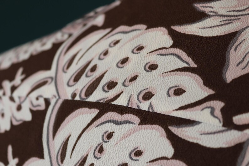 Peut inclure: Gros plan sur un tissu brun avec un motif floral blanc. Le tissu a une surface textur&eacute;e et les fleurs sont d&eacute;taill&eacute;es avec de petits points blancs.