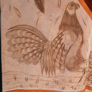 May include: A tan leather panel with a brown rooster design. The rooster is facing right and has a detailed tail. The panel has a brown border and a tan border with a repeating swirl design.