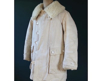 May include: Cream-colored winter coat with a sheepskin collar and button-up front. The coat has two front pockets and is displayed on a wooden mannequin. The coat is a vintage style.