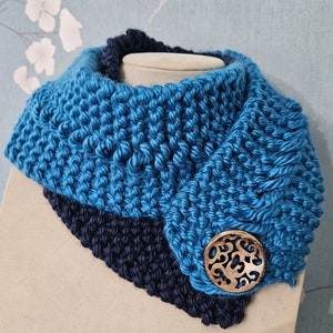 Puede incluir: Un cuello de punto azul y negro con un botón de madera. El cuello está doblado y el botón es visible en el lateral.