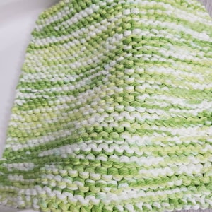 May include: A green and white striped knitted dishcloth. The dishcloth is made of a soft, absorbent material and is perfect for cleaning dishes, wiping down counters, or drying hands.