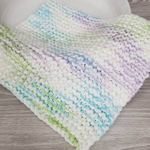 Puede incluir: Un paño de cocina de punto blanco con rayas de azul claro, verde y morado.
