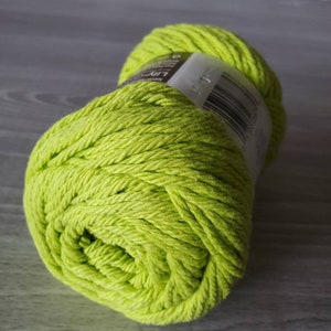 May include: A ball of bright green yarn. The yarn is made of cotton and is ready to be used for knitting or crocheting.