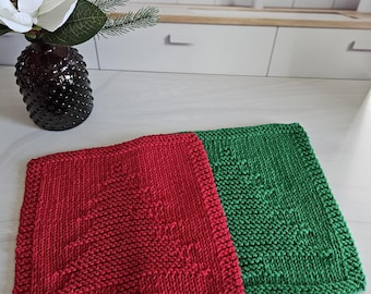 May include: Two knitted dishcloths with a Christmas tree design. One is red and the other is green.