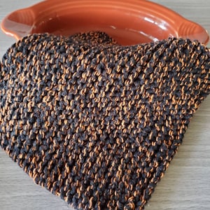 May include: A black and orange knitted dishcloth. The dishcloth is made of a soft, absorbent material and is perfect for cleaning dishes or drying hands.
