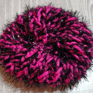 Puede incluir: Un gorro de lana rosa y negro con hilos brillantes.