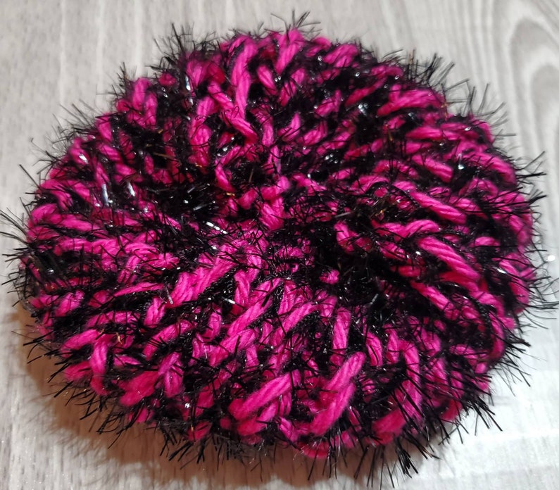 Puede incluir: Un gorro de lana rosa y negro con hilos brillantes.