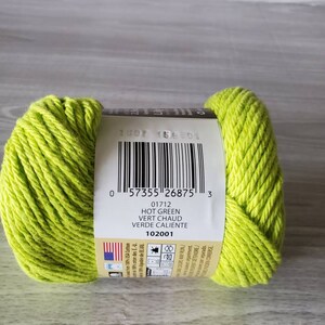 May include: A skein of bright green yarn with a label that reads "Hot Green, Vert Chaud, Verde Caliente" and the number "01712".