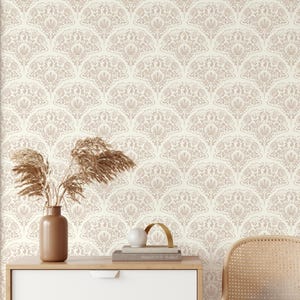 May include: Interior shot with cream floral wallpaper in a fan design. A white chest of drawers, a woven chair, and a vase with dried plants are positioned in front of the wallpaper, creating a cozy atmosphere.