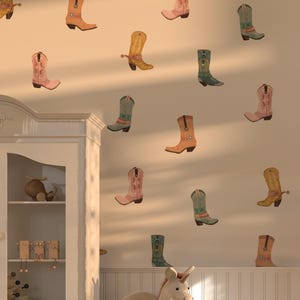 Puede incluir: Una habitación decorada con varias pegatinas de pared de botas de vaquero de colores. Un armario blanco, un perchero con faldas y una parte superior, y un unicornio de peluche también están en la habitación. La habitación tiene un ambiente cálido y acogedor.