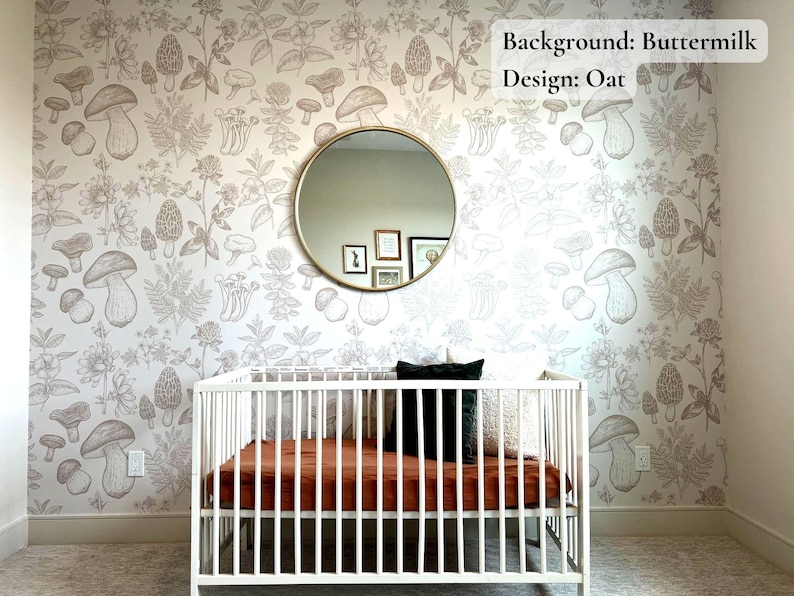 K&ouml;nnte beinhalten: Ein wei&szlig;es Babybett mit einer braunen Matratze und einem schwarzen Kissen in einem Kinderzimmer mit einer wei&szlig;en Wand, die mit einem Tapetendesign aus braunen Pilzen und Pflanzen verziert ist. Der Text "Background: Buttermilk Design: Oat" steht in der oberen rechten Ecke des Bildes.