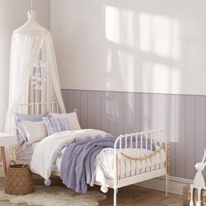 May include: A white metal bed frame with a white and purple bedding set. The bed has a white canopy with a light string of lights. There is a purple throw blanket on the bed and a wicker basket on the floor next to the bed.