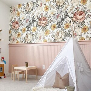 Puede incluir: Una tienda de campa&ntilde;a tipi blanca con una almohada a rayas marrones y blancas en su interior, instalada en una habitaci&oacute;n con papel tapiz floral y un z&oacute;calo rosa.