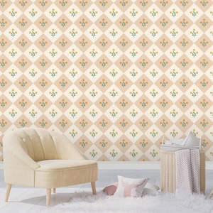 Op de afbeelding: Een gezellige interieurscène met een crèmekleurige fauteuil, een rieten mand en een decoratief kussen op een zachte witte vloerkleed. De achtergrond toont behang met een herhalend bloemenpatroon in beige, crème en geel.