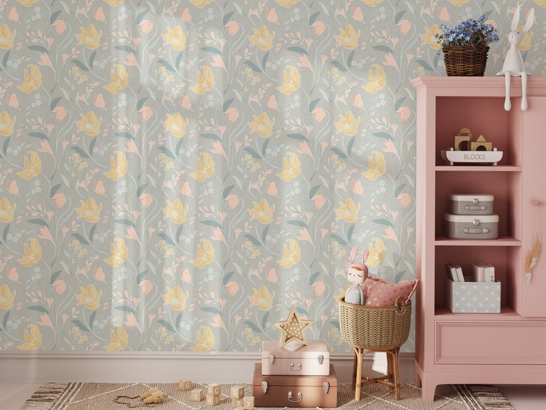 A child's room with pastel floral wallpaper, wooden toys on the floor, and a pink shelf with storage boxes