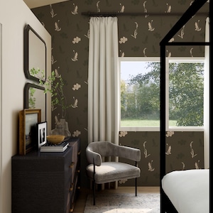 May include: A bedroom interior with a dark wood dresser, gold hardware, and a grey velvet armchair. The room features patterned wallpaper with floral and leaf motifs, a window with white curtains, and a black four-poster bed frame. The room has a rug.