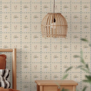 May include: A bedroom interior featuring a light brown wooden bed, a bedside table, and a pendant light. The walls are adorned with a beige wallpaper featuring a repeating pattern of small floral bouquets in blue and white vases. The wallpaper has a checkered pattern in a light blue colour.