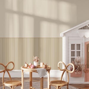 May include: A light brown wooden table with two chairs and a white playhouse in the background. The table is set with a white plate, a pink donut, and two small cups. The chairs are made of wicker and have a bow-shaped back.
