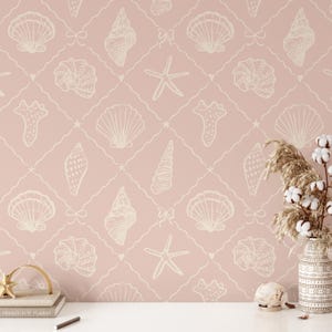 May include: Pink wallpaper with a repeating pattern of white seashells, starfish, and coral. The design includes a grid of lines with bows and hearts. A vase with dried plants and cotton stems sits on a white surface.