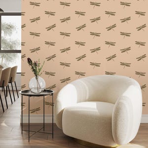 May include: A room with a cream-coloured, rounded armchair with a gold base. The wall is decorated with a repeating pattern of brown dragonflies on a peach background. A small, round table with a glass vase of flowers is also present.