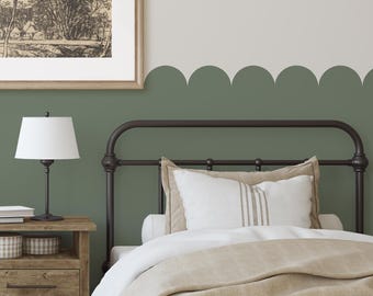 May include: A single bed with a white duvet and a tan throw blanket. The headboard is black metal and the bed is against a wall painted in two shades of green. A framed picture hangs above the nightstand.