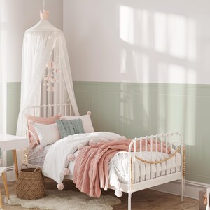Puede incluir: Una cama con estructura de metal blanco con una manta rosa y blanca y un dosel blanco sobre la cama. La cama est&aacute; en una habitaci&oacute;n con paredes verdes y molduras blancas.