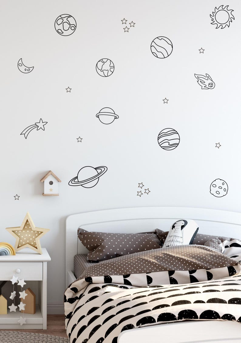 Kids bed with brown polka dot bedding under a wall filled with planets and stars decals.