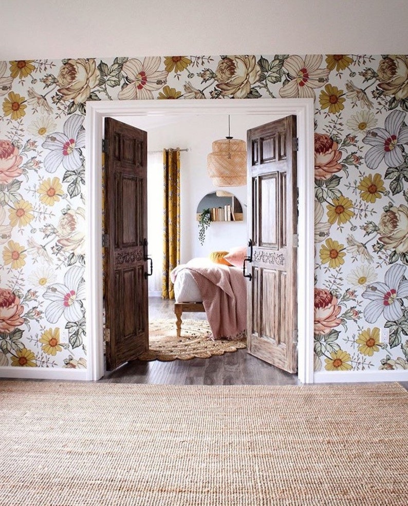 Puede incluir: Un dormitorio con papel tapiz floral, una cama con una manta rosa y una alfombra en el suelo. La habitaci&oacute;n tiene dos puertas de madera que conducen a otra habitaci&oacute;n.