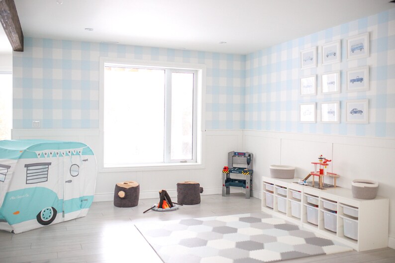 May include: A playroom with a blue and white gingham wallpaper, a white play kitchen, a camper tent, and a gray and white rug.
