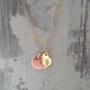 Puede incluir: Un collar de oro con un dije de coraz&oacute;n y dos dijes redondos con la letra K.