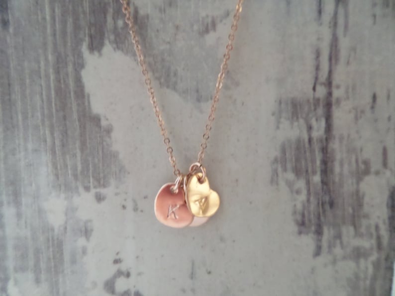 Puede incluir: Un collar de oro con un dije de coraz&oacute;n y dos dijes redondos con la letra K.