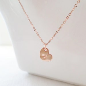 Puede incluir: Un collar de oro rosa con un colgante en forma de coraz&oacute;n. El colgante tiene un peque&ntilde;o dise&ntilde;o triangular en el centro.