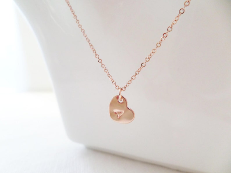 Puede incluir: Un collar de oro rosa con un colgante en forma de coraz&oacute;n. El colgante tiene un peque&ntilde;o dise&ntilde;o triangular en el centro.
