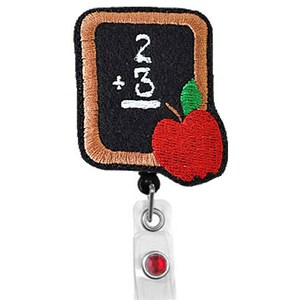 Peut inclure: Un badge brodé marron et noir avec un tableau noir et une pomme. Le tableau noir affiche l'équation "2 + 3". Le badge est attaché à un porte-badge rétractable en plastique transparent avec un bijou rouge.