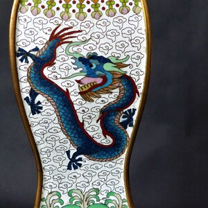 K&ouml;nnte beinhalten: Ein wei&szlig;es Emaille-Objekt mit goldfarbenem Rand und einem blauen Drachen-Design. Der Drache ist von einem Muster aus wei&szlig;en Wolken auf wei&szlig;em Hintergrund umgeben.