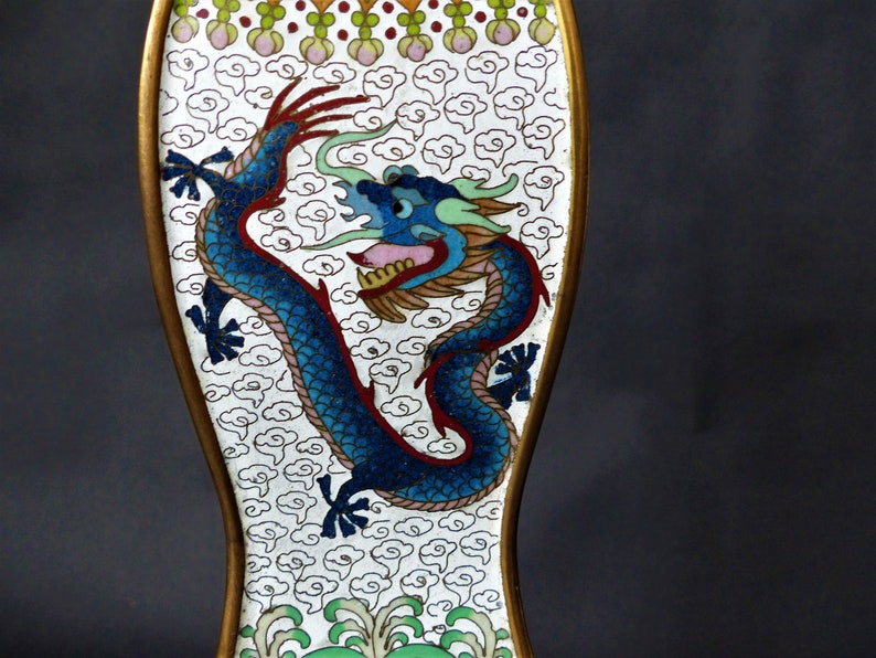 K&ouml;nnte beinhalten: Ein wei&szlig;es Emaille-Objekt mit goldfarbenem Rand und einem blauen Drachen-Design. Der Drache ist von einem Muster aus wei&szlig;en Wolken auf wei&szlig;em Hintergrund umgeben.
